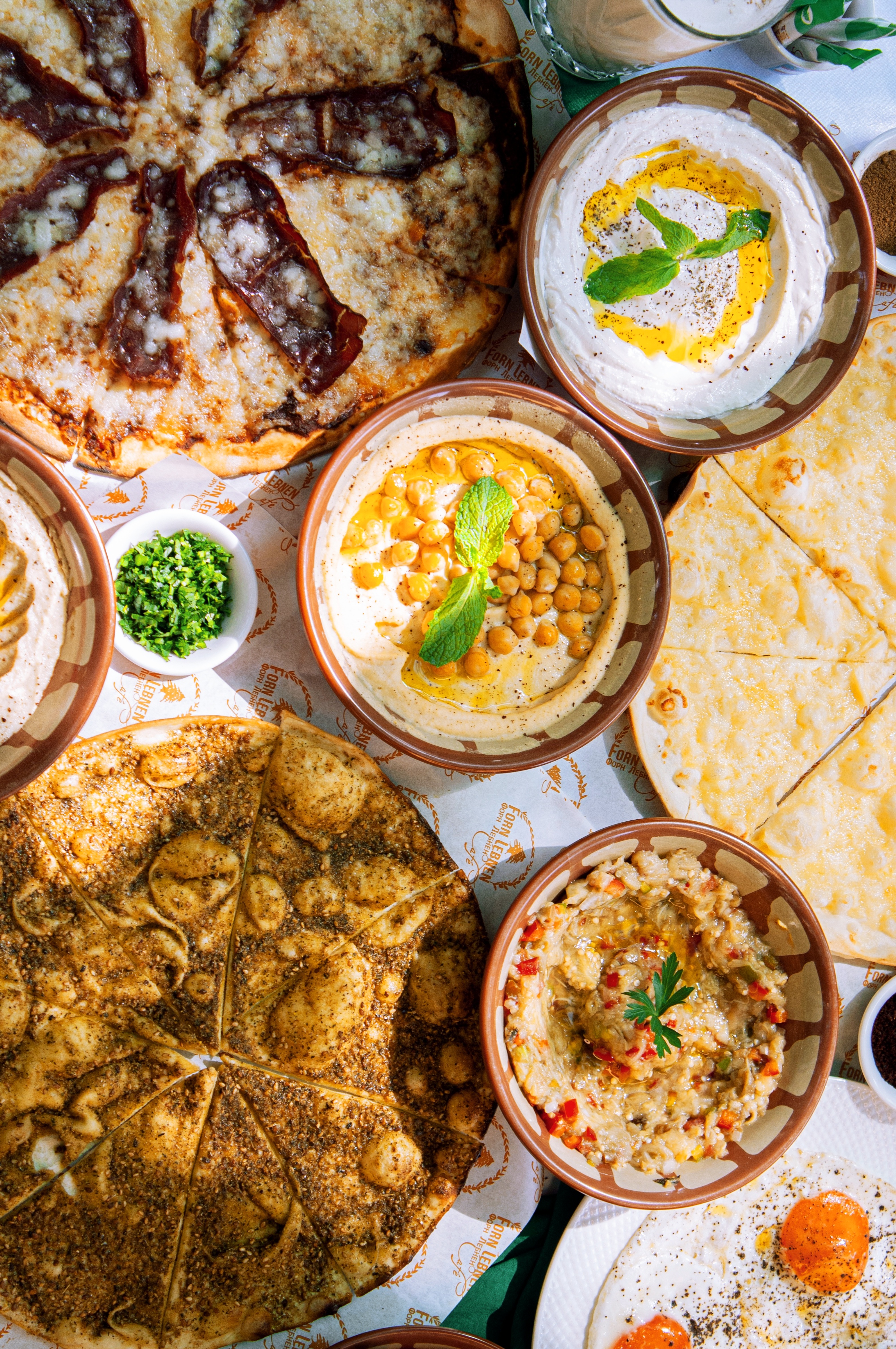 A spread of Forn Lebnen dishes including manakish, hummus, moutabal, and labneh